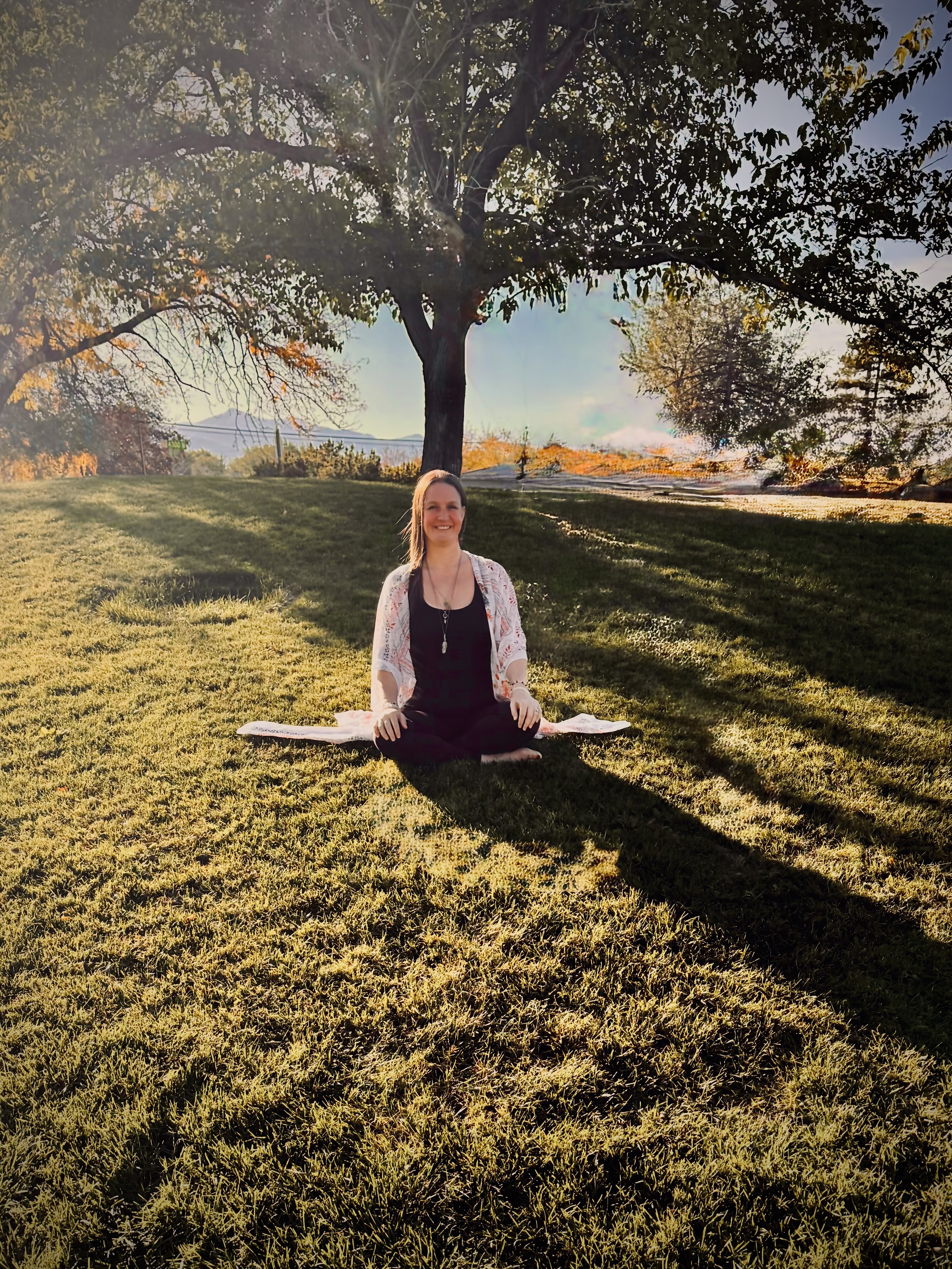 Born to Fly Healing founder meditating beneath a tree at golden hour